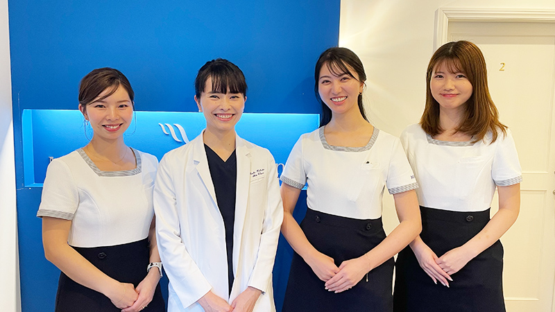 まいこホリスティックスキンクリニックの山﨑まいこ先生（中央）とスタッフ3名が並んで笑顔で撮影された集合写真。クリニックの明るく協力的な雰囲気が伝わる一枚。